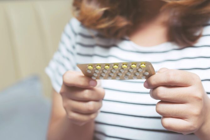 A close-up of a woman holding a birth control pill pack representing can you donate eggs on birth control.