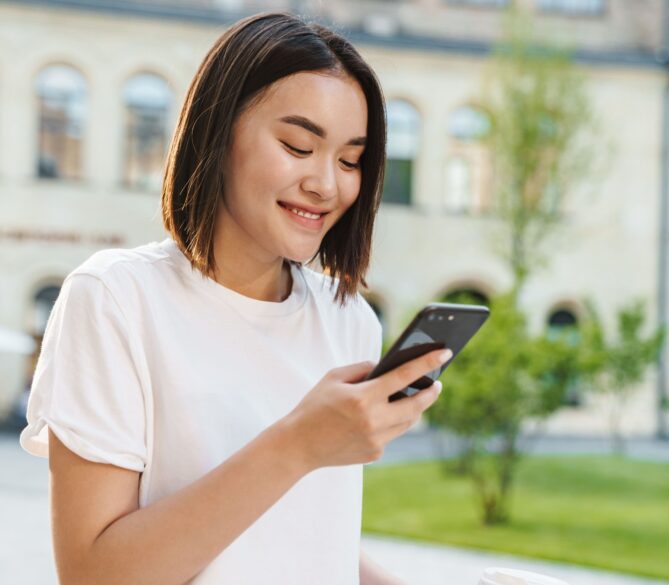 An Asian woman looking down at her phone representing how to become an egg donor.