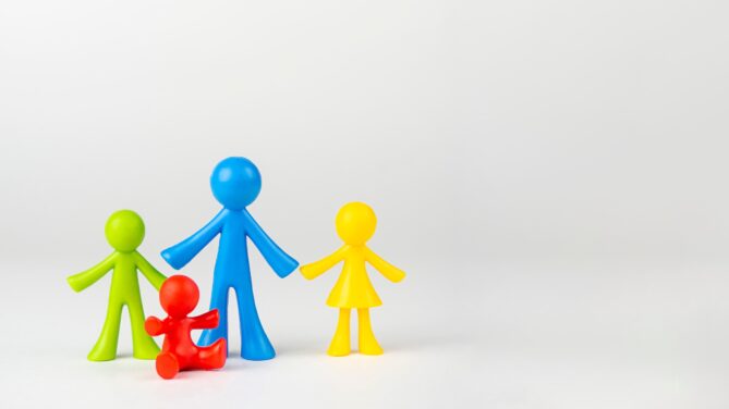 Four plastic multicolored toys representing a family stand on a white background representing egg donation.