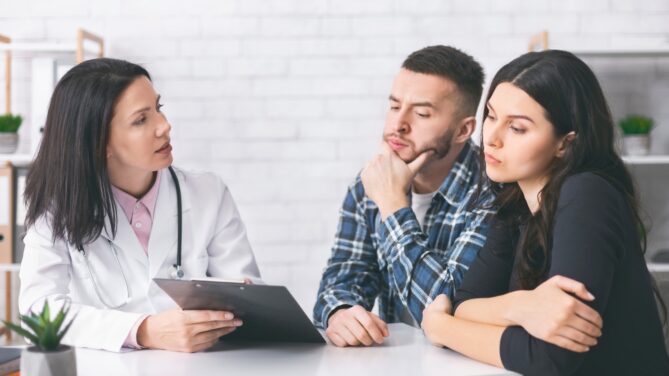 A couple talking to a doctor representing what is infertility.