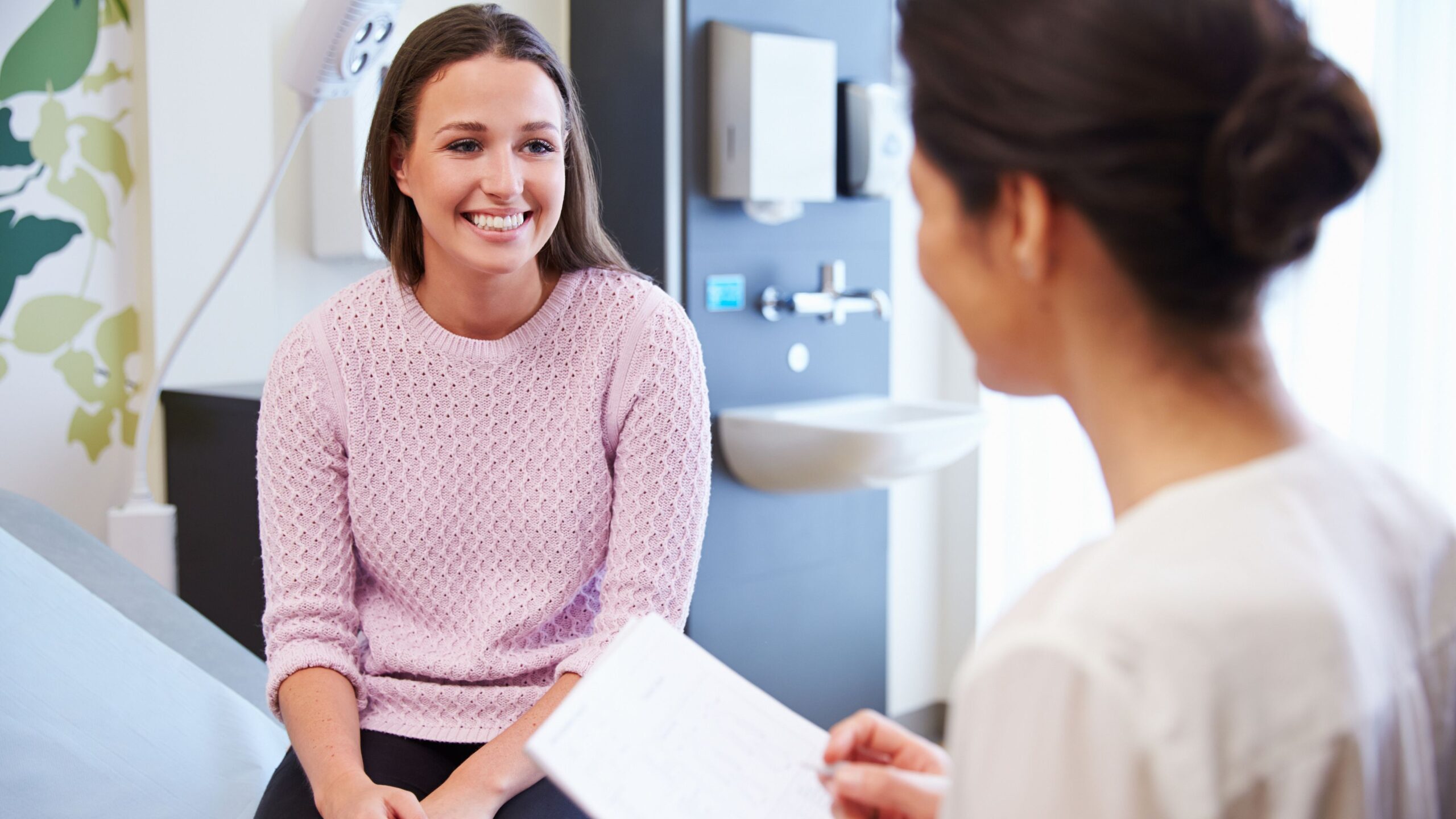 A female doctor is speaking with a happy patient about the prospect of donating her eggs while her tubes are tied