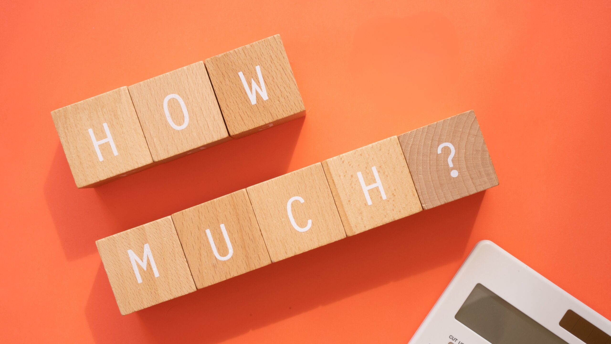 Building Blocks that spell out the words, how much? A white calculator cut off in the bottom right corner. The background is a apricot colored orange. Represents how much does a sperm donor cost.