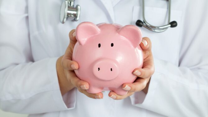 A doctor in a lab coat holding a pink piggy bank representing how much do sperm donors make