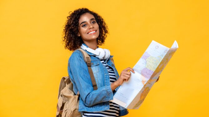 A woman holding a map in front of a bright mustard background representing How to Become an Egg Donor The Complete Guide.