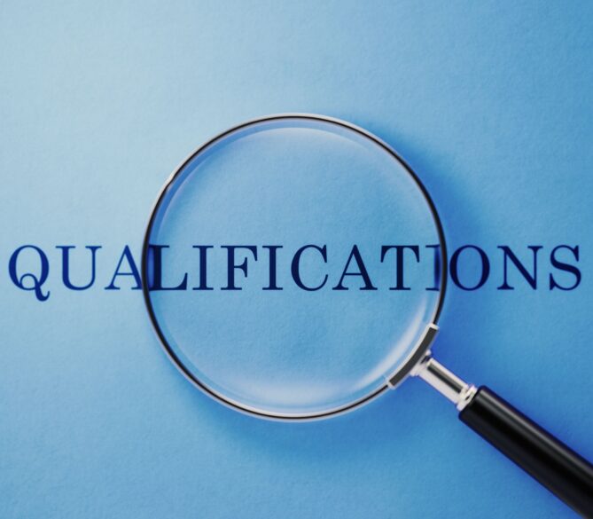 A large magnifying glass lays over the word qualifications representing the egg donor qualifications.