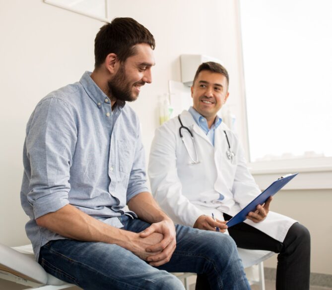 A man sitting next to a doctor in a doctors office representing how many times can you donate sperm.