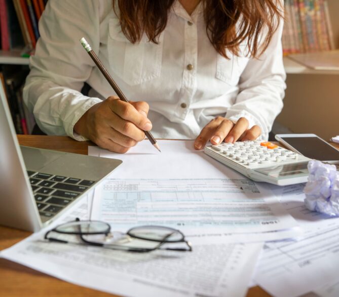 A woman sitting at her desk crunching numbers representing how much does a sperm donor cost.