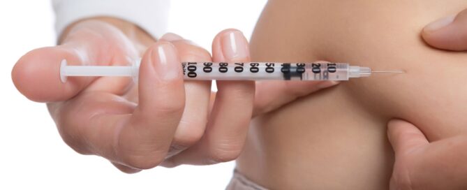 Close-up of woman injecting her stomach with a needle.